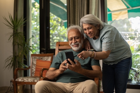 happy elderly couple looking at phone